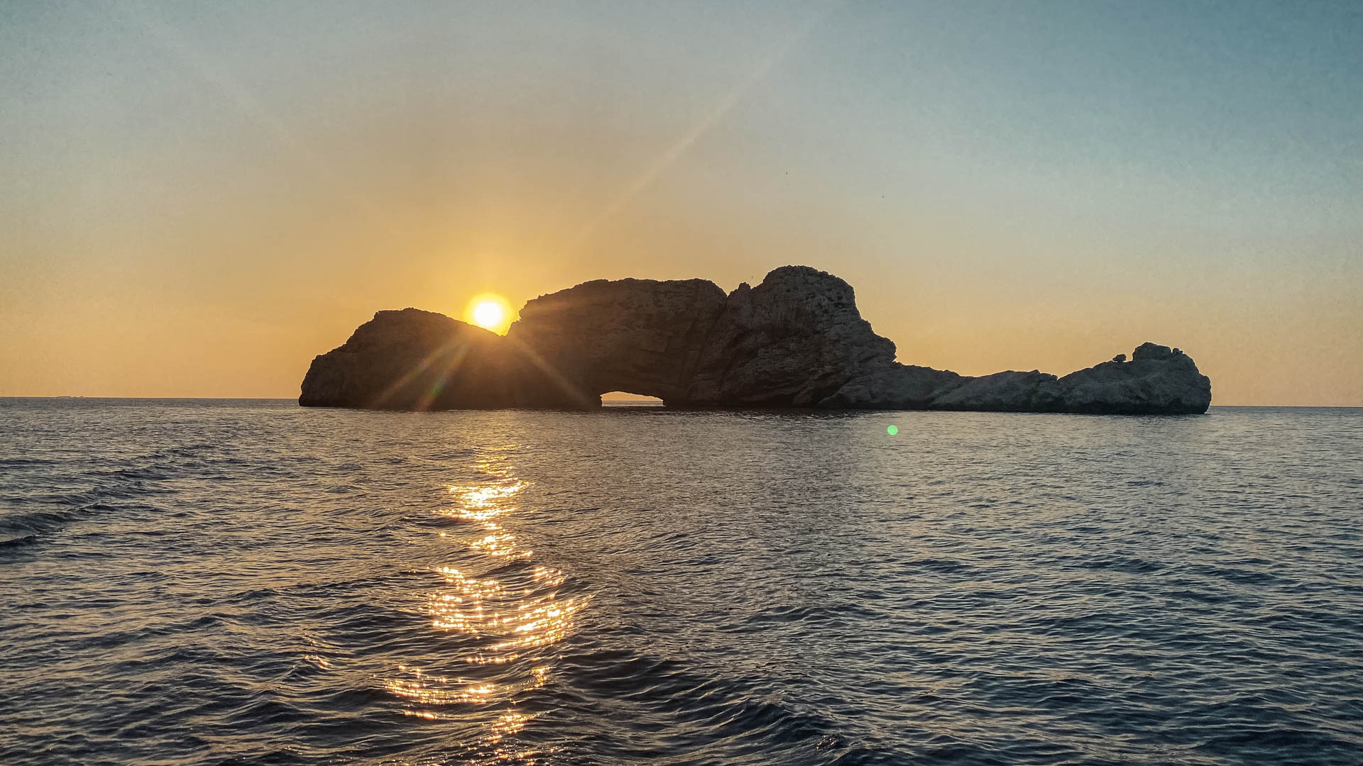 Sun setting behind Es Vedra seen from the boat